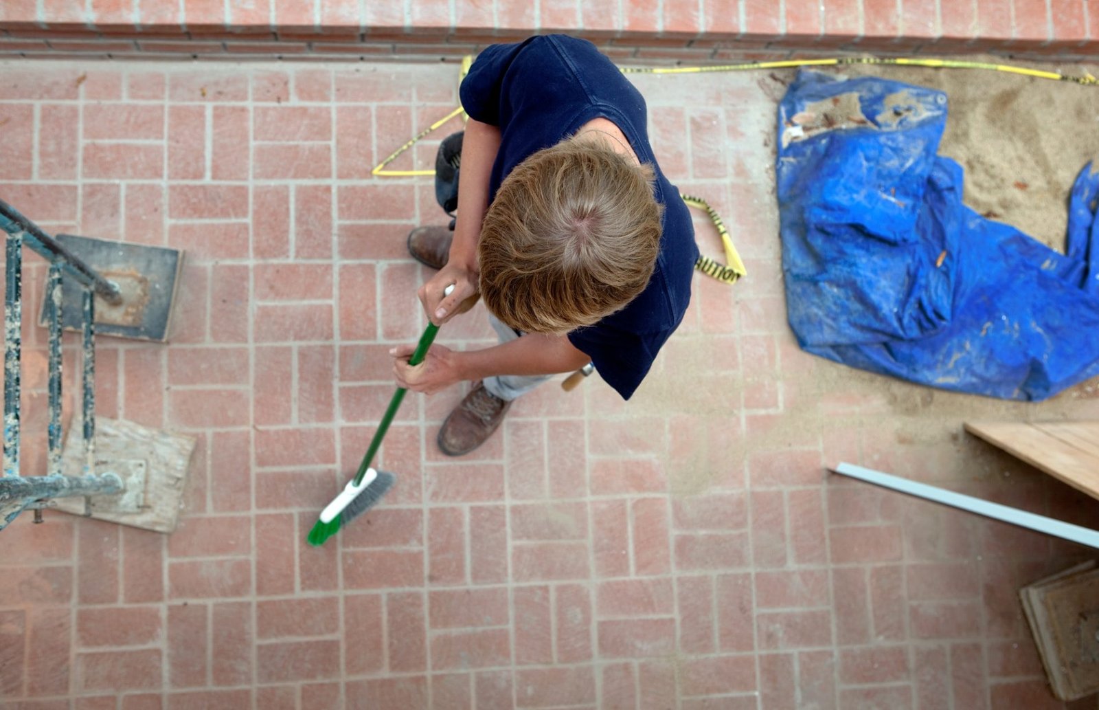 Teenage boy sweepingn on construction site